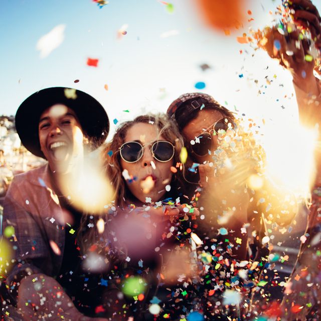 teenager hipster friends partying by blowing colorful confetti from hands