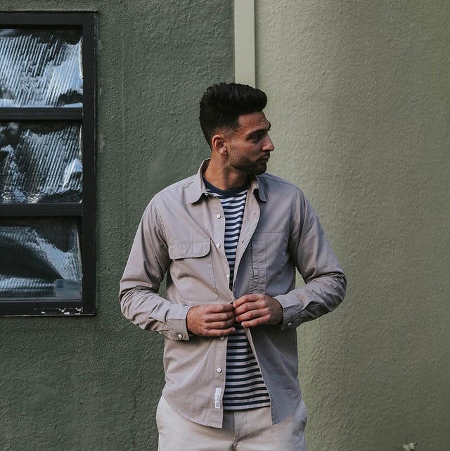 man buttoning shirt