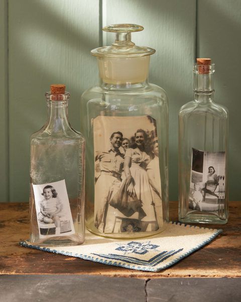 black and white photos in glass jars sitting on a brown table in from of a green wall