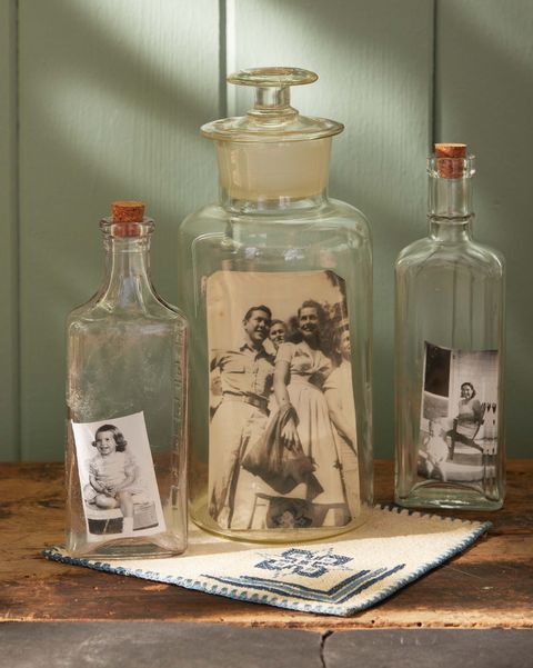 vintage photos nestled in antique glass bottle sitting on a wood table