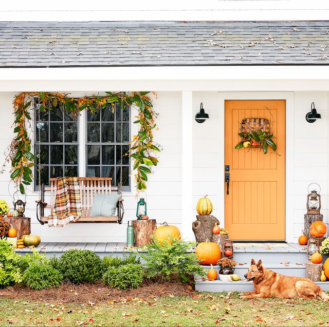 front porch with swing and orange door decorated for fall