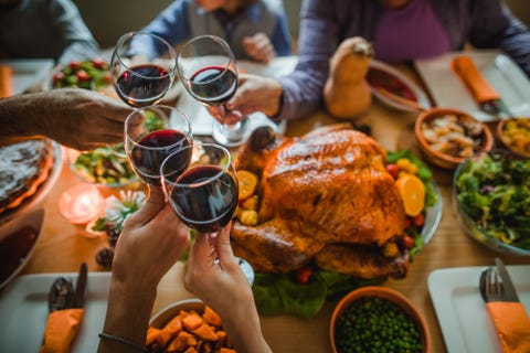 group of unrecognizable people toasting with wine during thanksgiving dinner at dining table