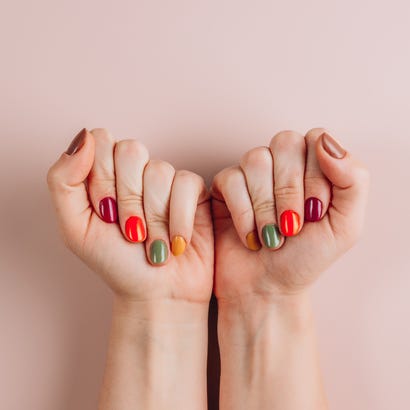 thanksgiving nails bold stylish trendy autumn female manicure in orange, brown, purple, green and yellow color womans hands on powdery pastel background