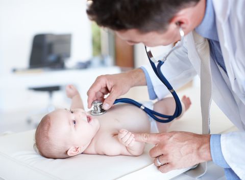 un pediatra ausculta a un bebé tumbado en una camilla