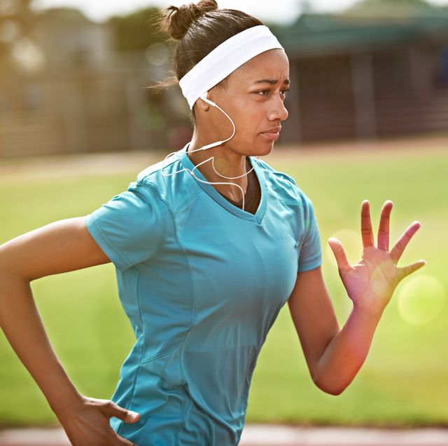 hardlopende vrouw trekt een sprint op de atletiekbaan met hoofdband in het haar
