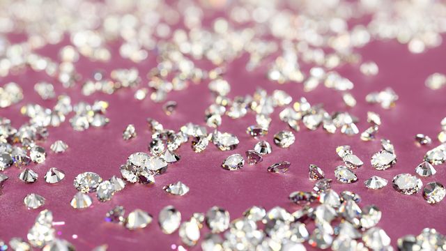 sparkling loose diamonds on pink background with shallow depth of field