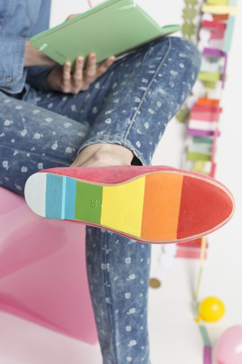 bottom of a shoe on a woman's foot painted rainbow colors in red, orange, yellow, green, blue and white