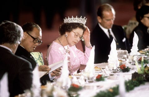 queen adjusts her tiara at a banquet table