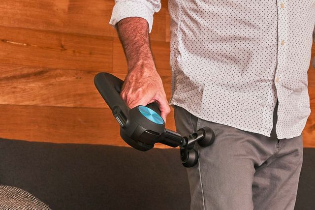 a man using a massage gun with two heads on his leg