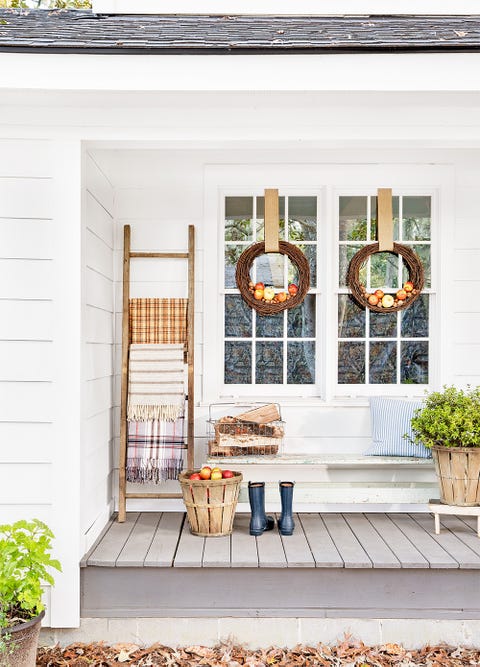 house front porch decorated for thanksgiving with apples nestled grapevine wreaths and ladder covered in plaid blankets