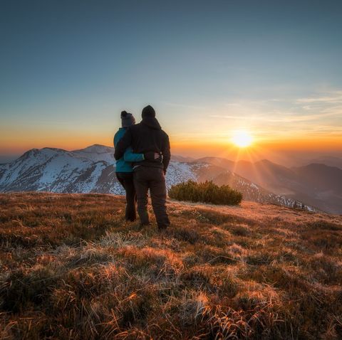 couple standing on hill at sunset