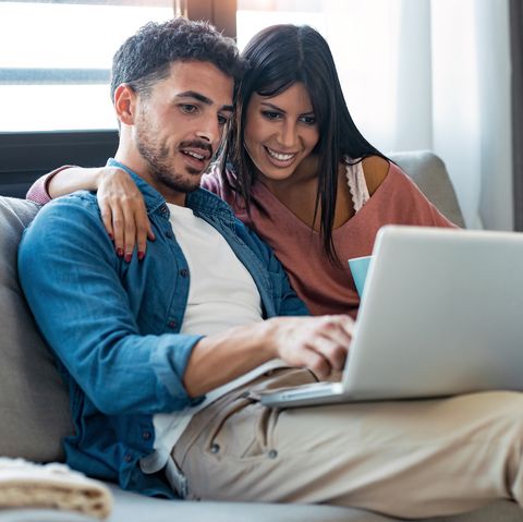 shot of happy beautiful couple using computer while sitting on the couch at home