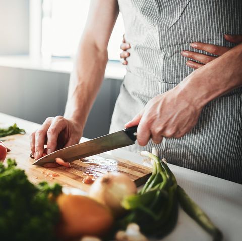 man chopping vegetables with womans hand on his waist