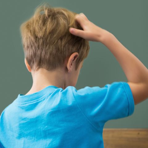 Thinking pupil scratching his head in classroom