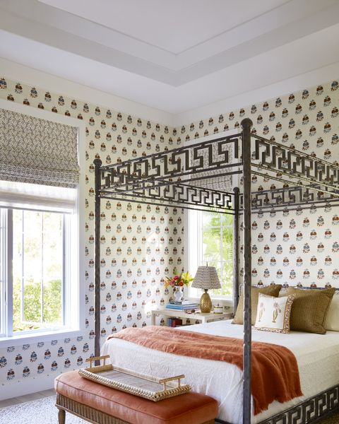 a guest room has a hammered metal bed and patterned wallpaper