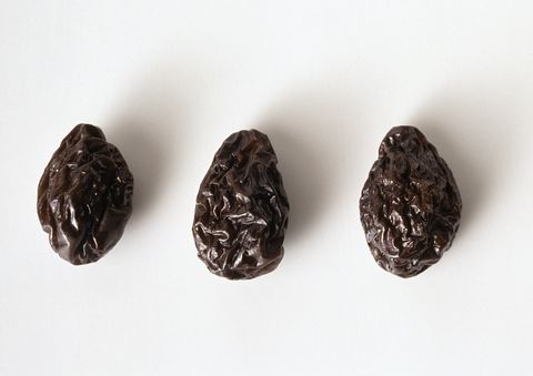 Three prunes against white background, close-up