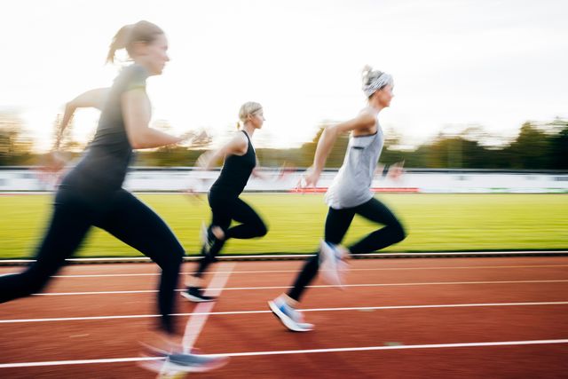 three women sprinting on outdoor running track