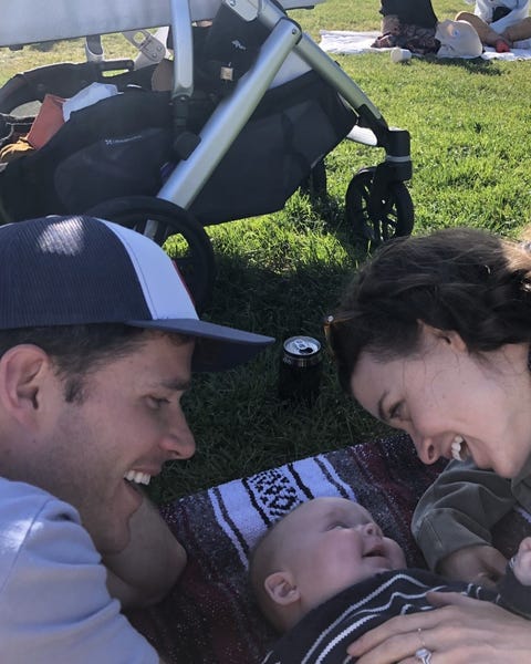 carly leahy and her husband charlie with their baby lying on a blanket in the park