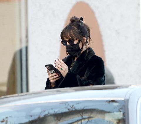 12112020 premium exclusive dakota johnson sparks engagement rumors after flashing a massive emerald green stone on her ring finger the 31 year old actress was spotted shopping at the elder statesman in west hollywood johnson wore a face mask, long teddy coat, checkered blouse, grey joggers, and dr martens tassel loafers salestheimagedirectcom please bylinetheimagedirectcomexclusive please email salestheimagedirectcom for fees before use