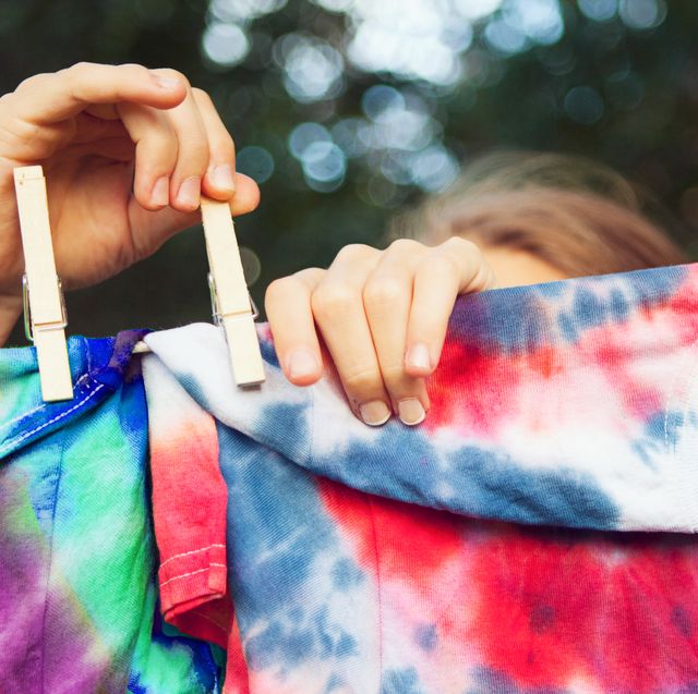 girl pinning tie dyed tshirts to clothes line
