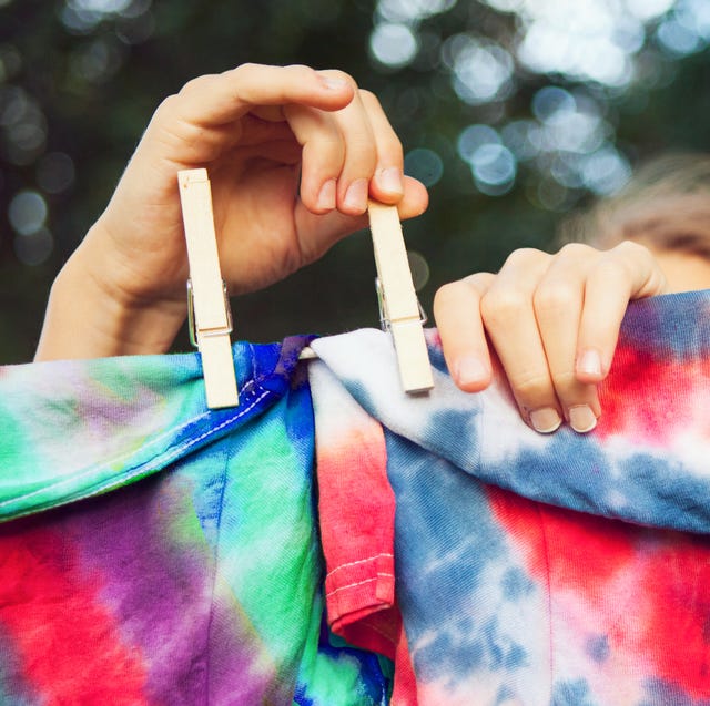 girl pinning tie dyed tshirts to clothes line