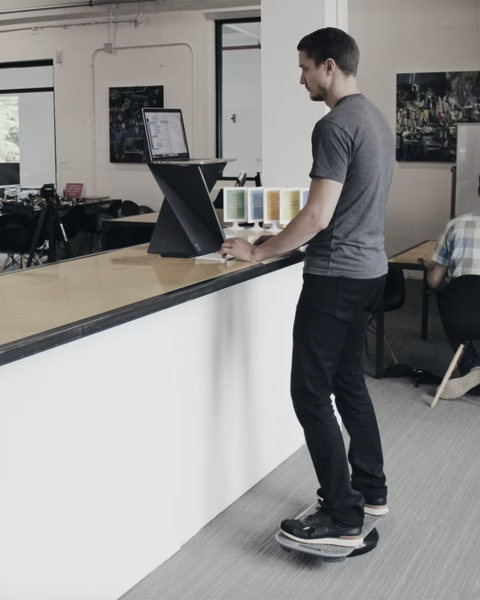 a man working at his laptop while standing on a 
revolution balance boards revbalance focus