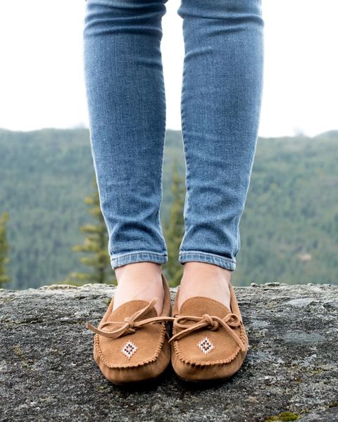 a person standing on a rock wearing manitobah loafers