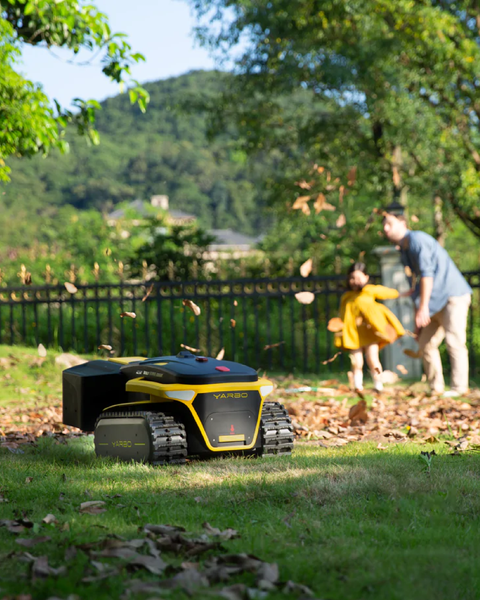 a yarbo lawn mower mowing a lawn as a man and child watch