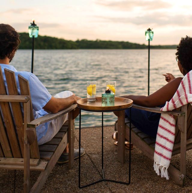 couple sitting next to lake with glass tiki torches