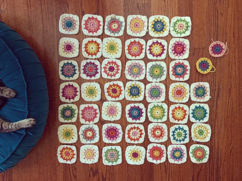 Tiny colorful granny squares crocheted and spread on the floor