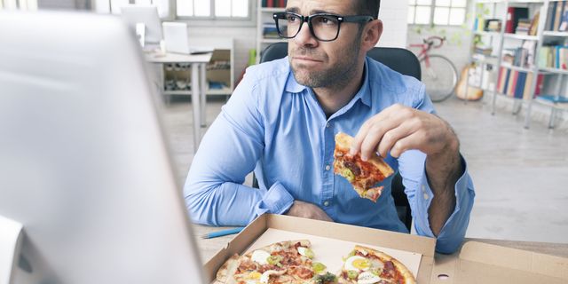 tired businessman eating pizza at the office