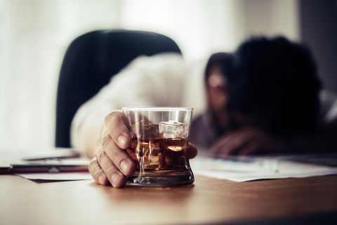 Tired Businessman Holding Whiskey Glass On Office Desk