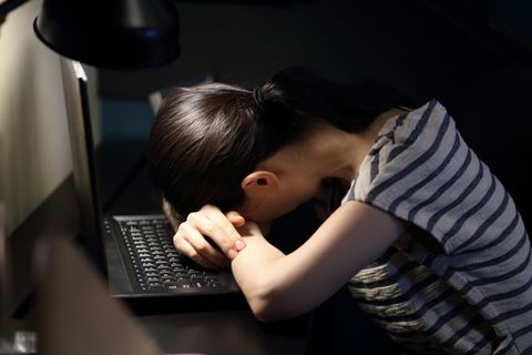 tired woman with head in hand on desk at home