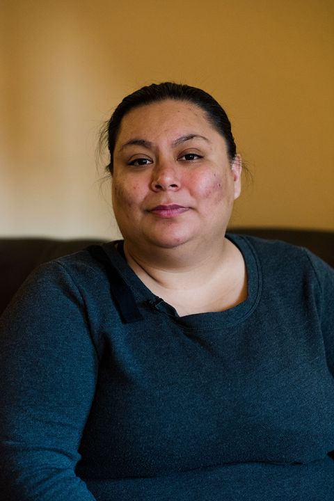 portrait of sex trafficking survivor, tish, wearing a dark blue shirt, sitting on a couch at home