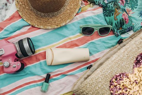 toalla de playa con gafas de sol y crema solar