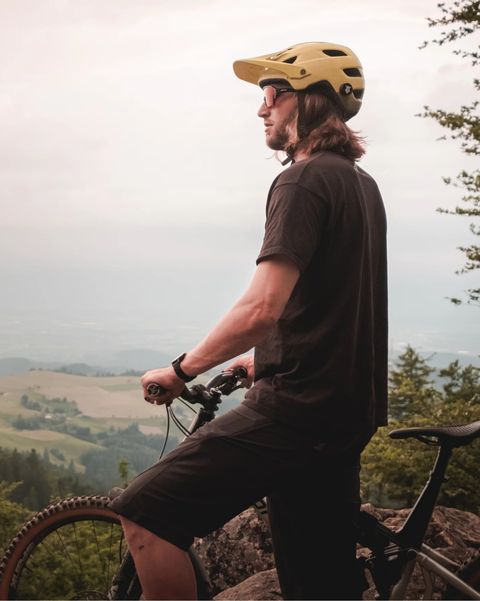 man wearing tocsen helmet crash sensor standing next to bike