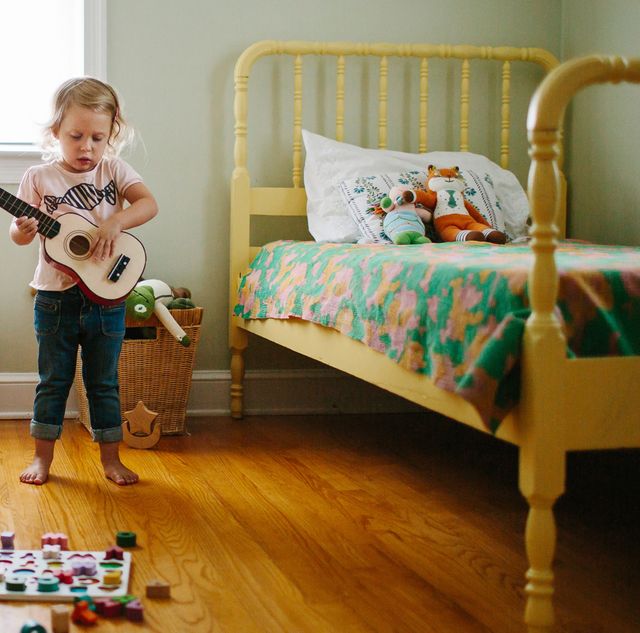 toddler playing guitar in bedroom with two yellow beds