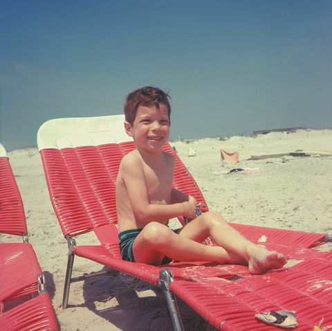 portrait of an unidentified boy in swimming trunks as he sits on a deckchair on the beach at fire island, new york, august 1965 he holds a box of cracker jack popcorn in his hands photo by dolly sotogetty images
