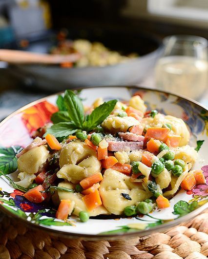 tortellini primavera with peas and carrots on floral plate