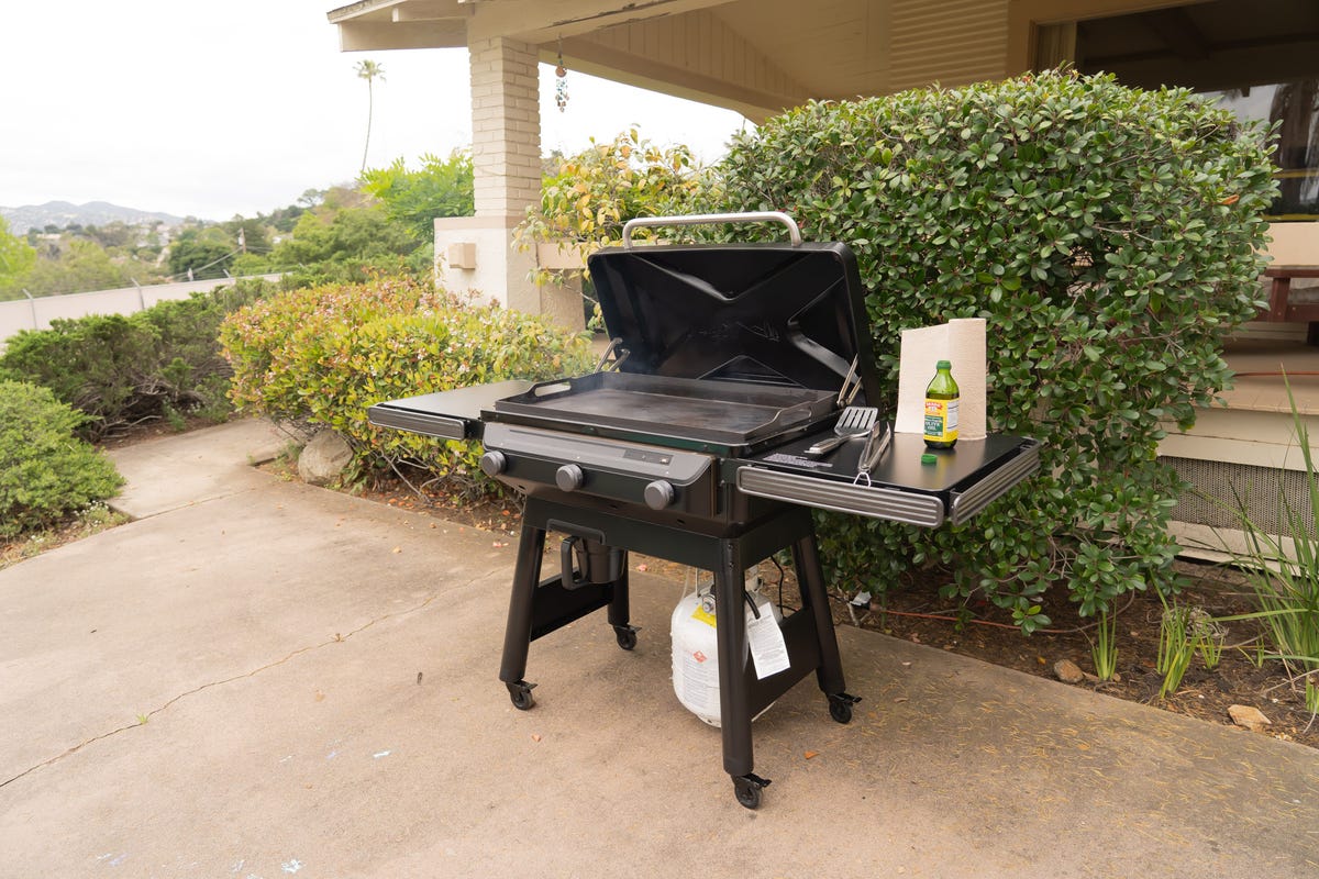 Grilling bacon strips on cast iron griddle in outdoor gas grill