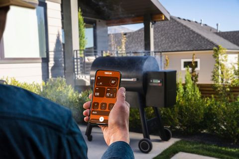 a man looking at his phone screen to monitor his Traeger Grill