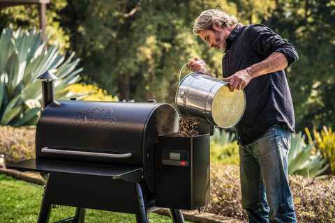 a man adds wood pellets to a Traeger grill