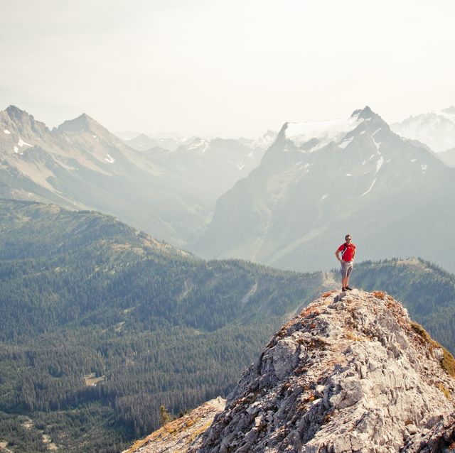 trail runner stands on the airy summit of a rocky mountain ridge