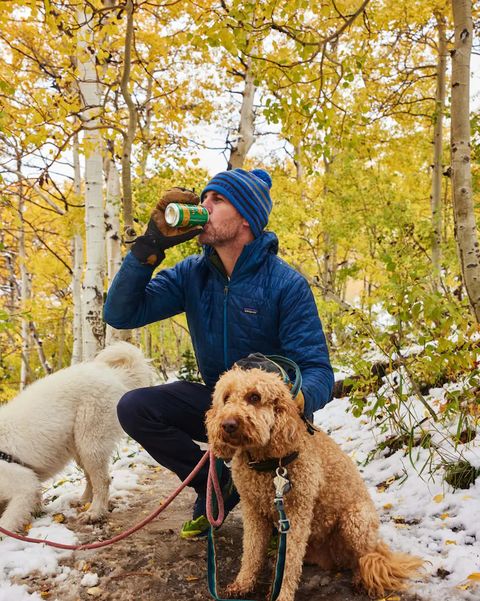 a person drinking a can of sierra nevada beer crouched by a dog