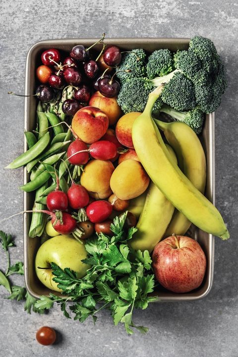 a tray of fresh vegetables and fruits on gray background