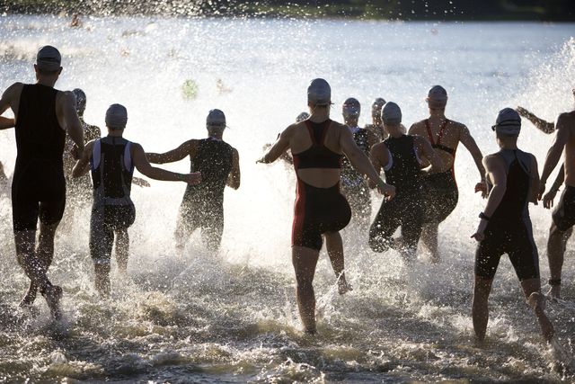 triathletes at start of triathlon running into the water