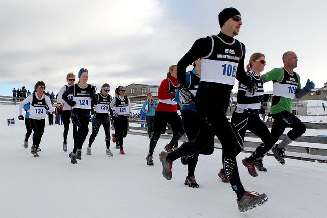 varios corredores corren sobre la nieve en un triatlón de invierno