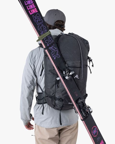person carrying raide backpack and skis