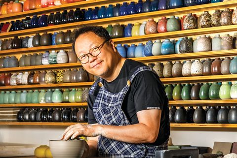 tung chiang, head of heath ceramics' recording studio in san francisco, in front of the company's signature bud vases