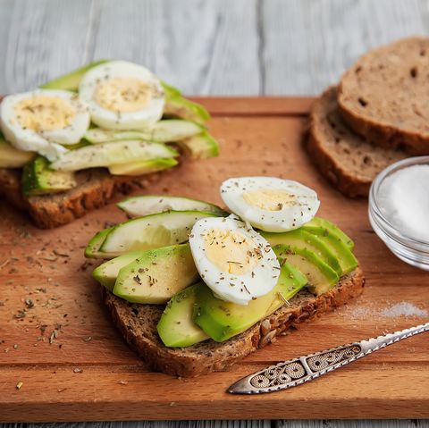 two avocado sandwiches with egg and spices on a wooden Board